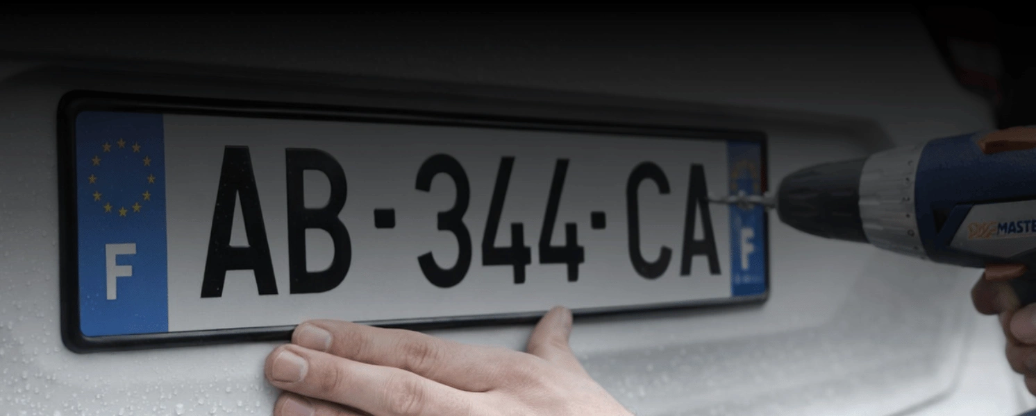 Personne qui visse une plaque d’immatriculation